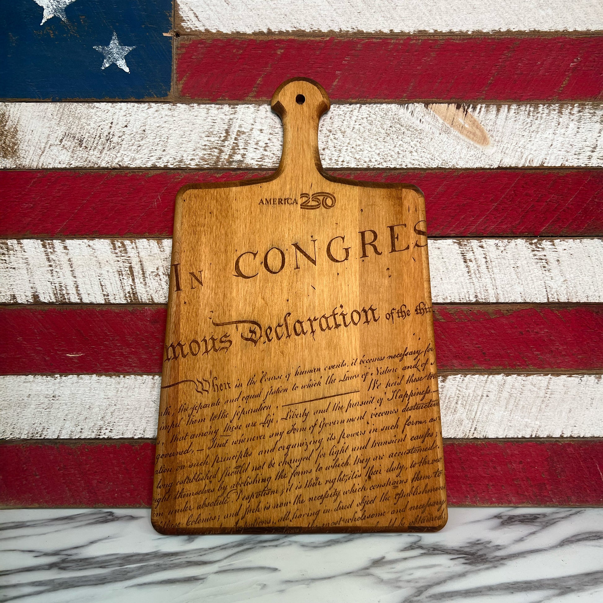 Wooden cutting board with engraved text on an American flag background.