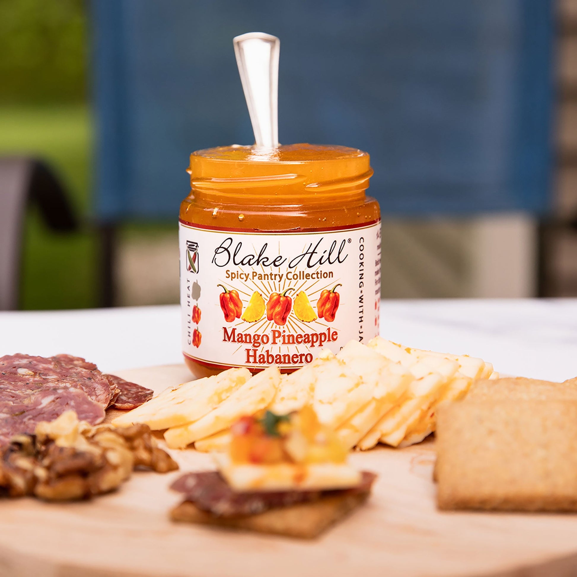 Jar of Blake Hill Mango Pineapple Habanero on a charcuterie board with various foods.