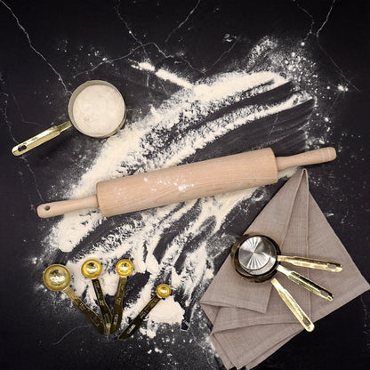 A rolling pin on a dark stone counter with flour and baking tools.  