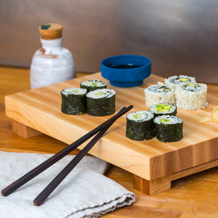 A maple block cutting board with sushi, soy sauce and chopsticks. 