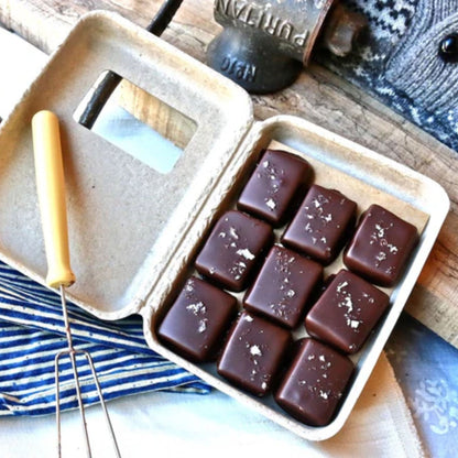 Box of chocolate candies with a wooden handle tool on a rustic background