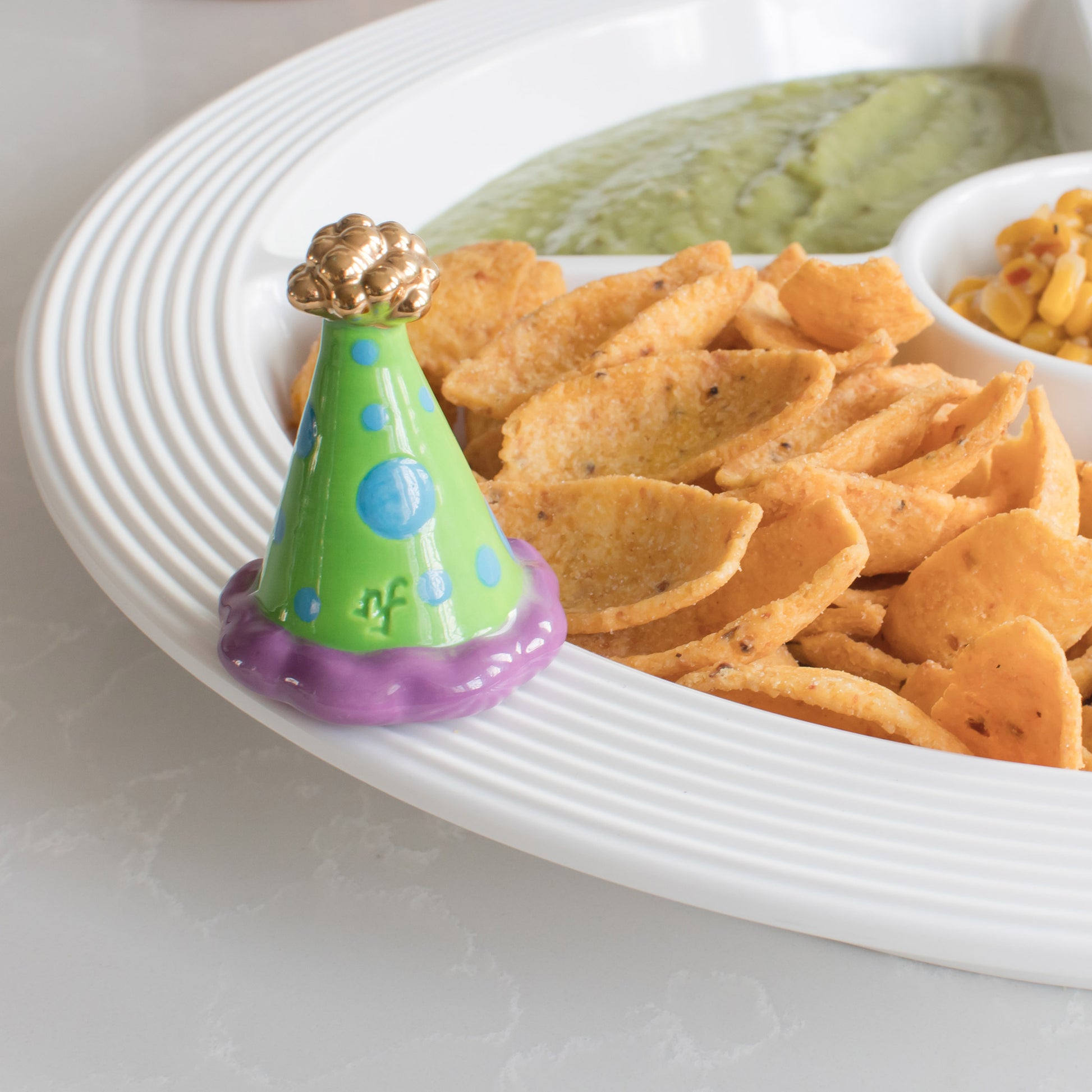 Colorful party hat on a plate with chips and guacamole